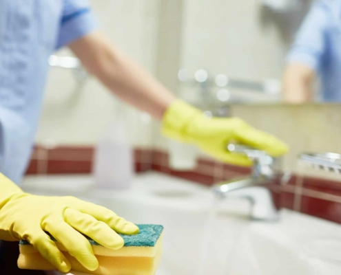 Janitor Cleaning Up Public Bathroom In Business Building