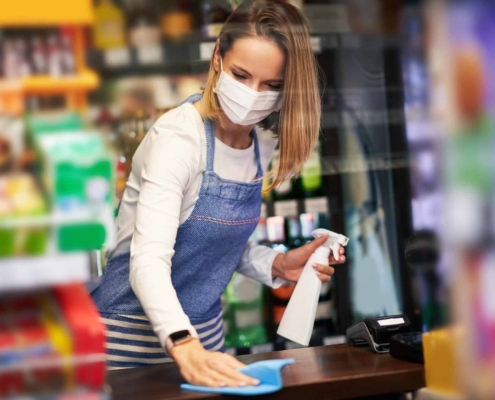Image-of-a-worker-in-a-grocery-store-sanitizing-a-checkout-counter. Image of a worker in a grocery store sanitizing a checkout counter.