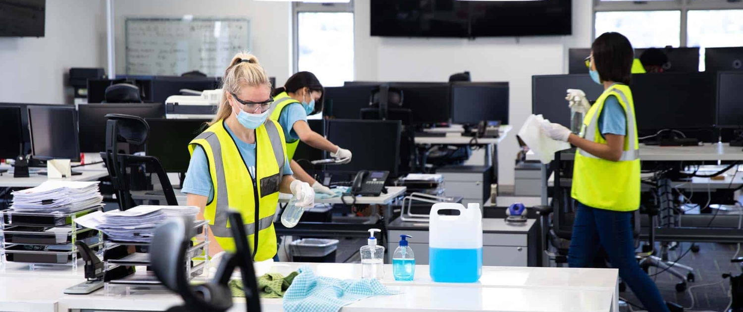 Team wearing hi vis vest and face mask cleaning the office using disinfectant