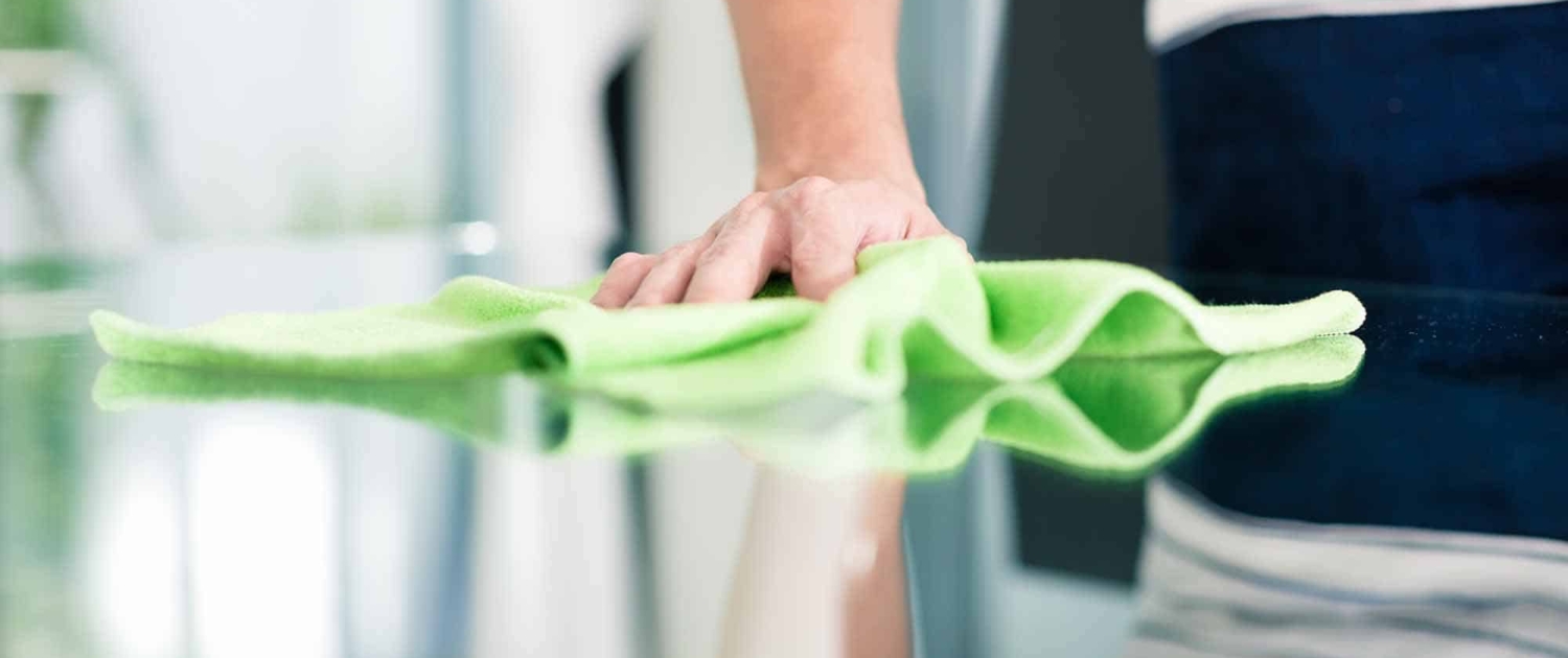 close up of a hand cleaning a glass table