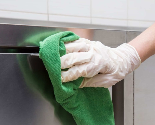 Commercial cleaning company wiping down kitchen bench
