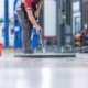 Janitor cleaning floor of warehouse