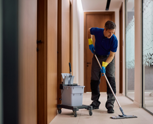 Commercial Cleaner Using Mop While Cleaning Office Hallway